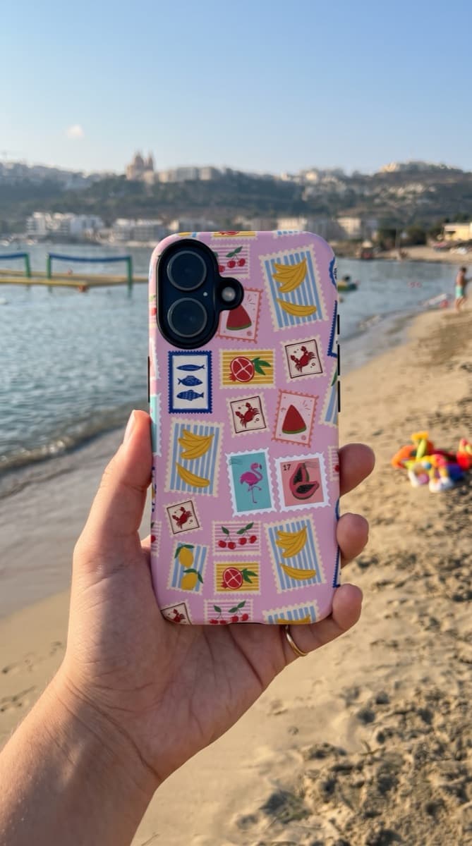 Stamp-pattern Avellé case held up on a beach in Mellieha, Malta