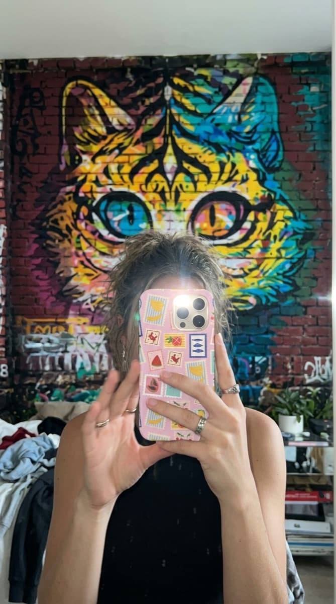 Stamp-pattern Avellé case in a mirror selfie against a mural